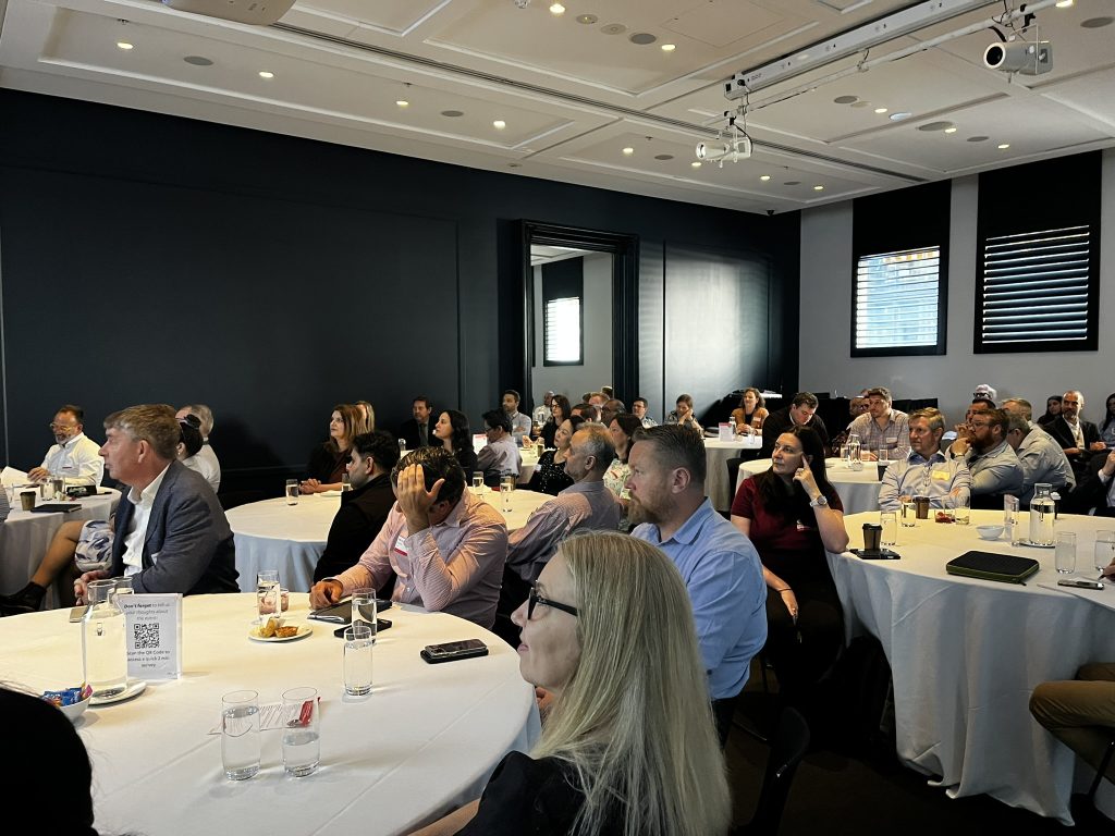 Audience of Transdev Australia and New Zealand employees seated at round tables listening attentively during the 2025 Transdev Sydney Light Rail Safety Forum.